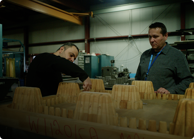 Team inspecting a wooden mold in the workshop